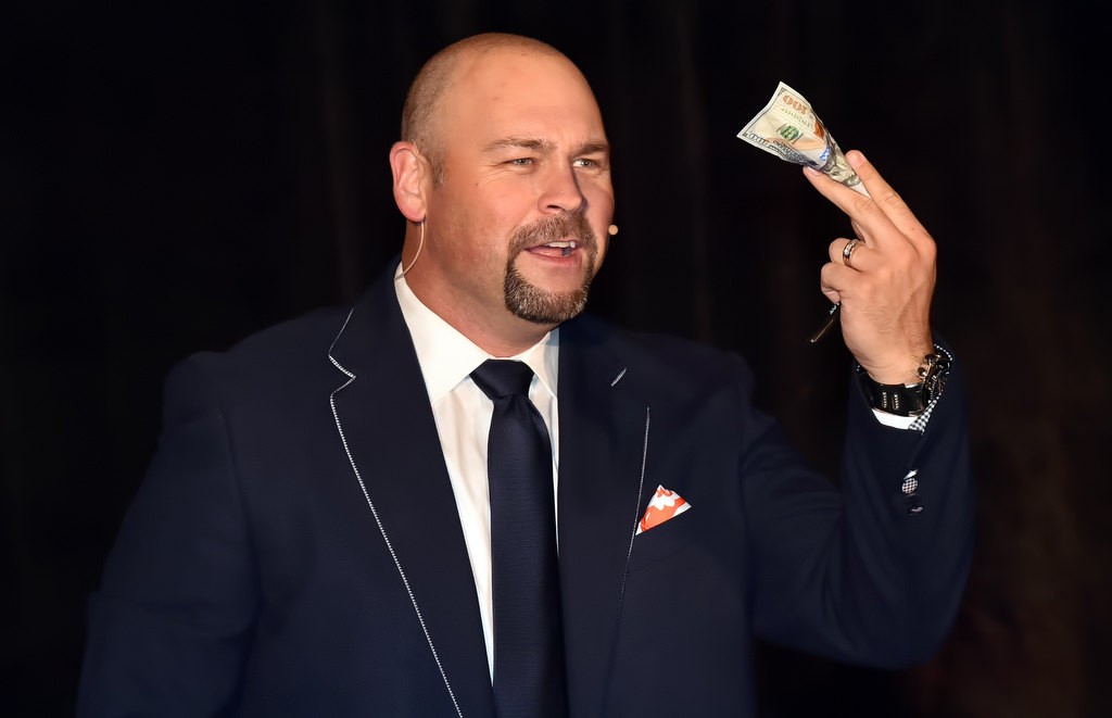 Matt Rogers, MC and the night’s auctioneer, holds up a $100 bill as the first item to auctioned off for the night. The bill sold for $5,000 benefiting the OCFJC Foundation. Photo by Steven Georges/Behind the Badge OC