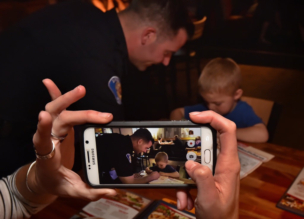 Garden Grove PD Officer Sean Gleason helps 3-year-old Emerson Collier of Rancho Santa Margarita with his coloring as mom takes a photograph during the Tip a Cop charity event at a Red Robin restaurant to raise money for Special Olympics. Photo by Steven Georges/Behind the Badge OC