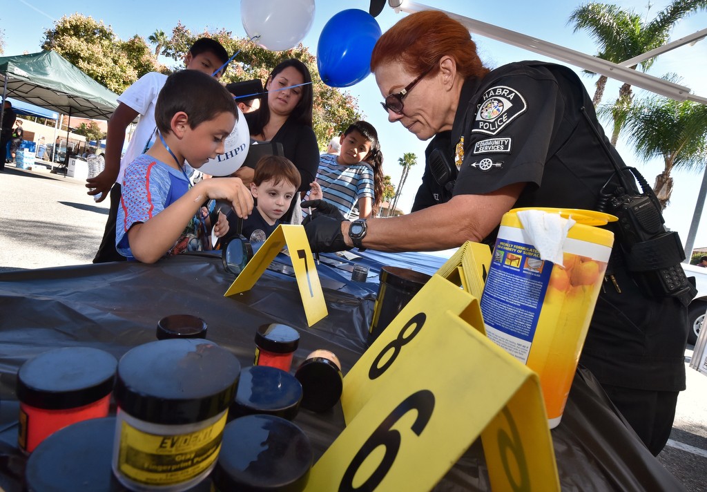 Christina Nunez, CSO (Community Services Officer), shows kids how to bring out fingerprints the kids left on a mirror at the CSI booth for La Habra PD’s open house. Photo by Steven Georges/Behind the Badge OC