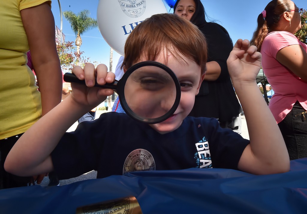 Four-year-old Kalel Carrera of La Habra checks out a magnifying glass at the CSI booth for La Habra PD’s open house. Photo by Steven Georges/Behind the Badge OC