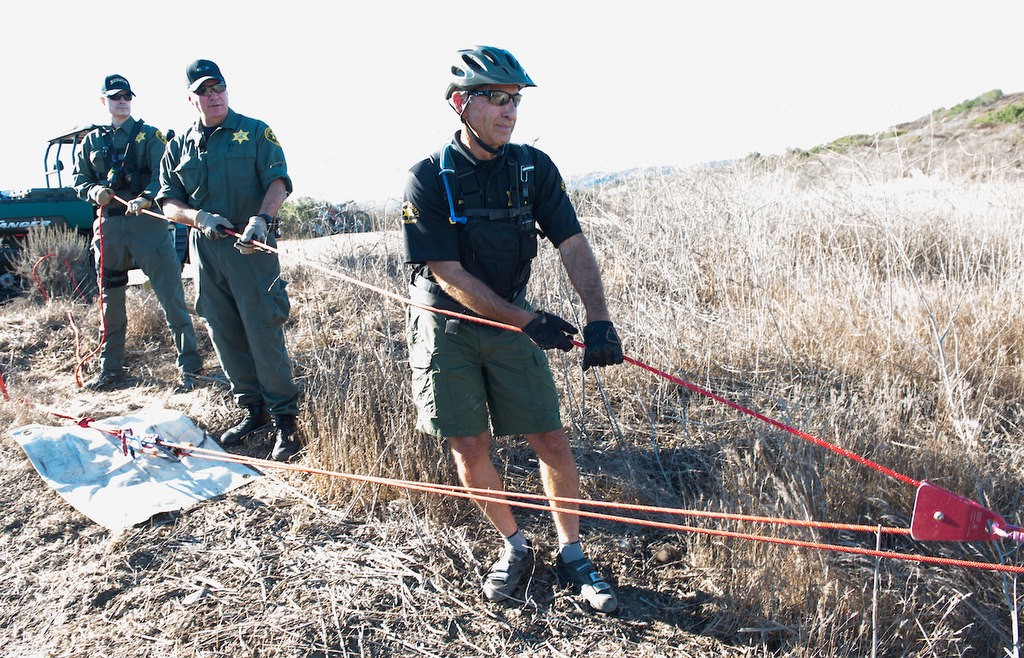 Members of the Orange County Sheriff's Search and Rescue Team Sgt. Michael Geoghan, left, Captain Chuck Williams and Deputy Gary Ziebarth help to pull up a litter as they demonstrate the process of finding a lost subject in the Aliso Woods Wilderness Park.