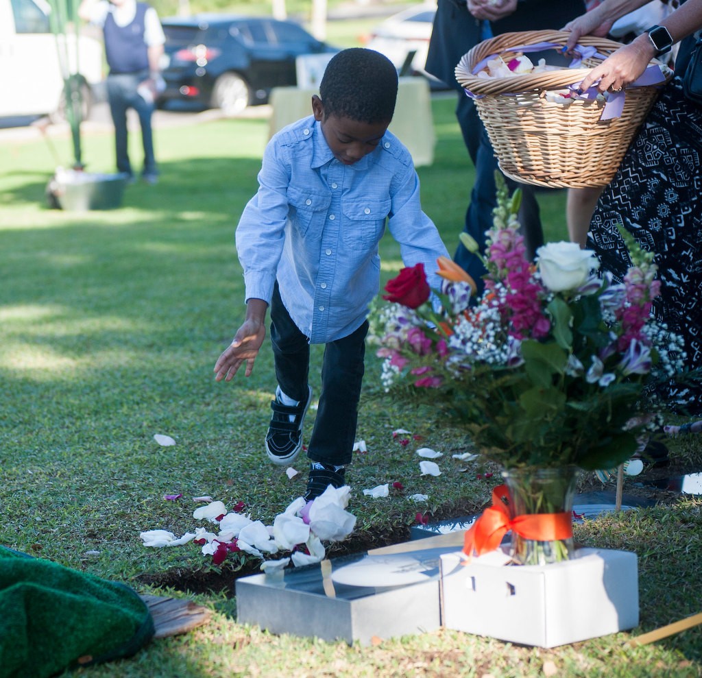 Emmitt Moran, 4, places flowers in the grave during the memorial service and burial of baby Kathleen, an unidentified infant who was given a name and memorial through the Garden of Innocence program. Photo by Miguel Vasconcellos