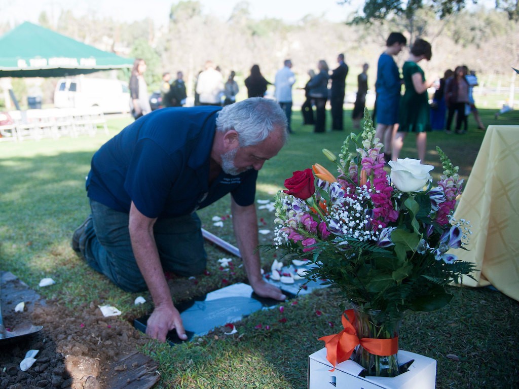 El Toro Memorial Park Cemetery Manager Bud Bales places the marker for  baby Kathleen in her grave following the conclusion of the memorial service for the unidentified infant.  The Orange County Garden of Innocence project provided her with a name and a burial site.