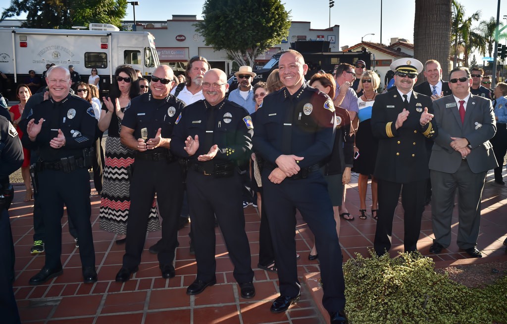 A crowd of well wishers, including Chief George Crum of Cathedral City PD (former Fullerton PD Captain), left, Chief Corey Sianez of Buena Park PD, Chief Tom Kisela of Orange PD, Chief Raul Quezada of Anaheim PD, Chief Wolfgang Knabe of Fullerton/Brea Fire and Council Member Greg Sebourn, applaud Fullerton Police Chief Dan Hughes during his Walk of Honor retirement ceremony. Photo by Steven Georges/Behind the Badge OC