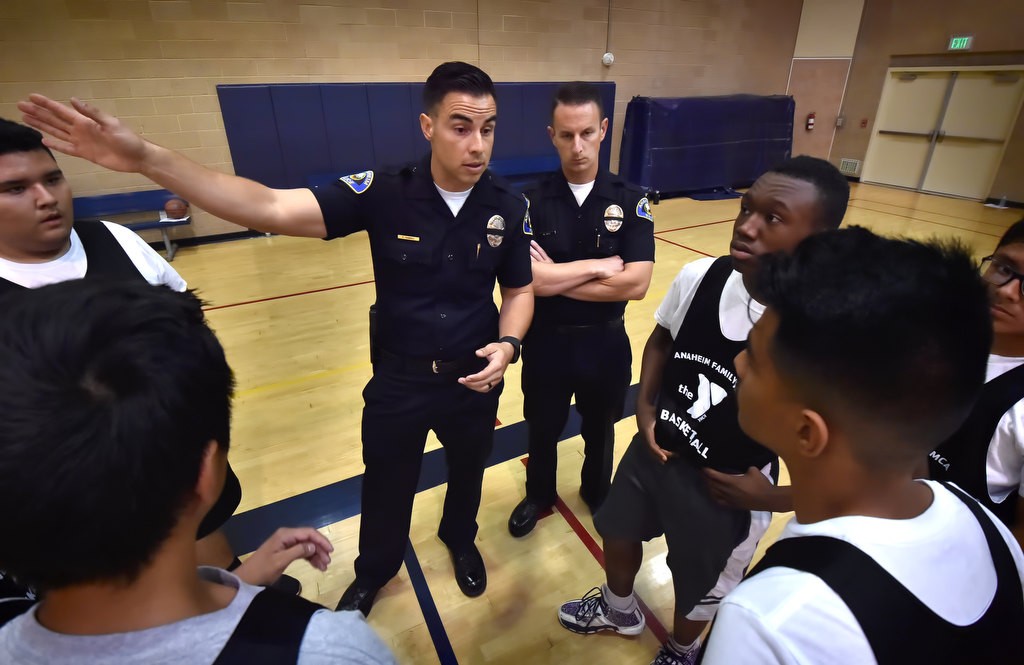 Anaheim PD officers Frank Ramirez, left, and Mark Gell give their players advice during timeout at a basketball game at the West Anaheim Youth Center. Photo by Steven Georges/Behind the Badge OC