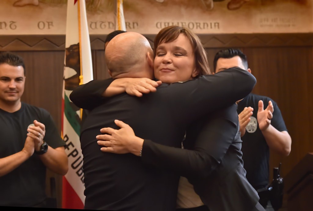 Fullerton PD Chief Dan Hughes receives a hug from Orange County Assistant District Attorney Tracy Miller as he was honored during an OC GRIP meeting. Photo by Steven Georges/Behind the Badge OC