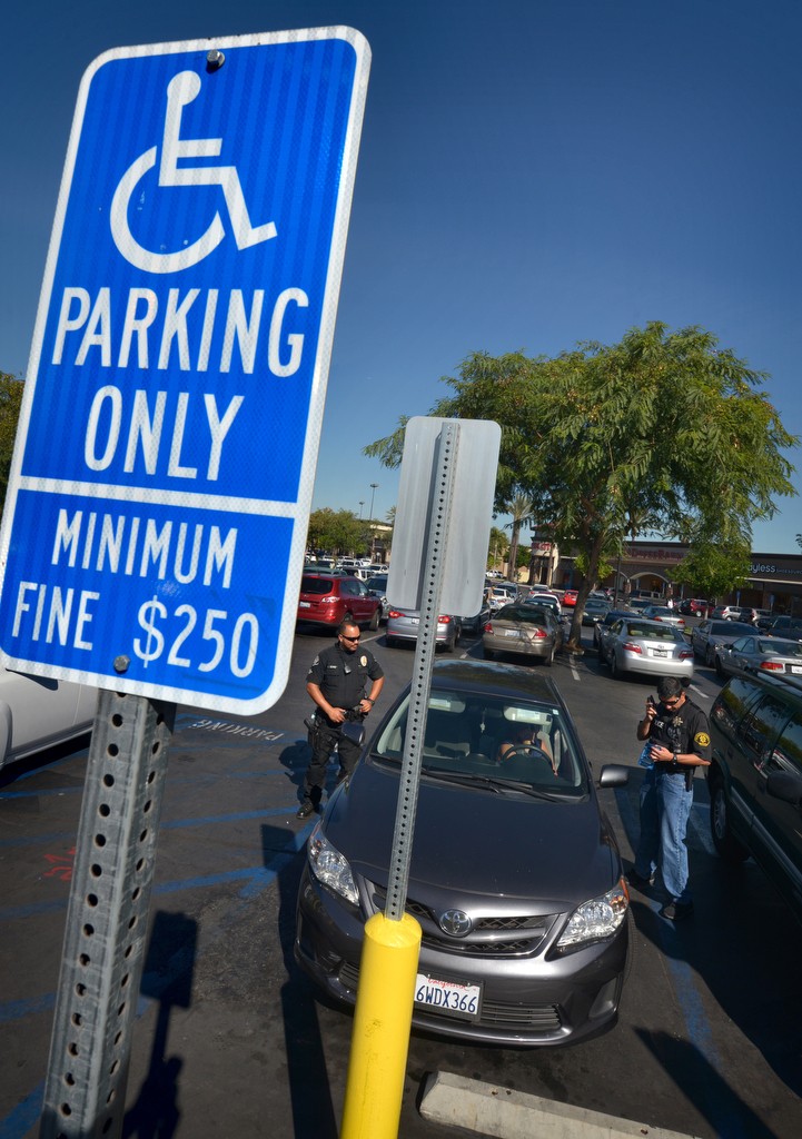 La Habra PD Officer Sumner Bohee, left, and DMV Investigator Luis Hernandez checks the credentials of a woman in the handicap parking space at Sam’s Club in La Habra. Photo by Steven Georges/Behind the Badge OC