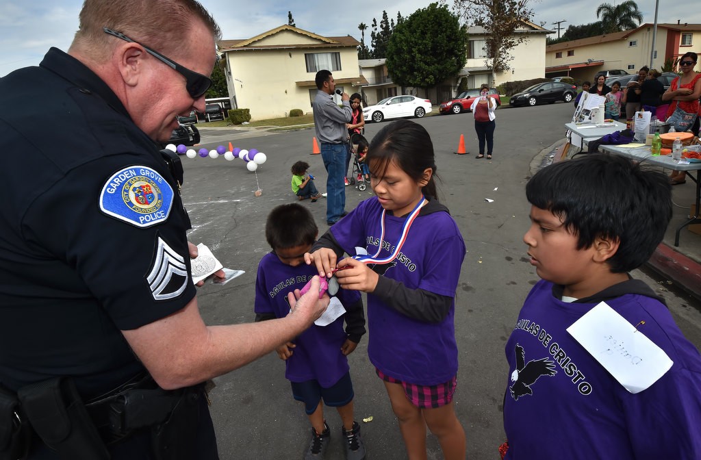 Elizabeth, 10, shows Garden Grove PD Sgt. Jon Wainwright a medal she won during a community gathering at the Palma Vista Ave. neighborhood in Garden Grove. Photo by Steven Georges/Behind the Badge OC