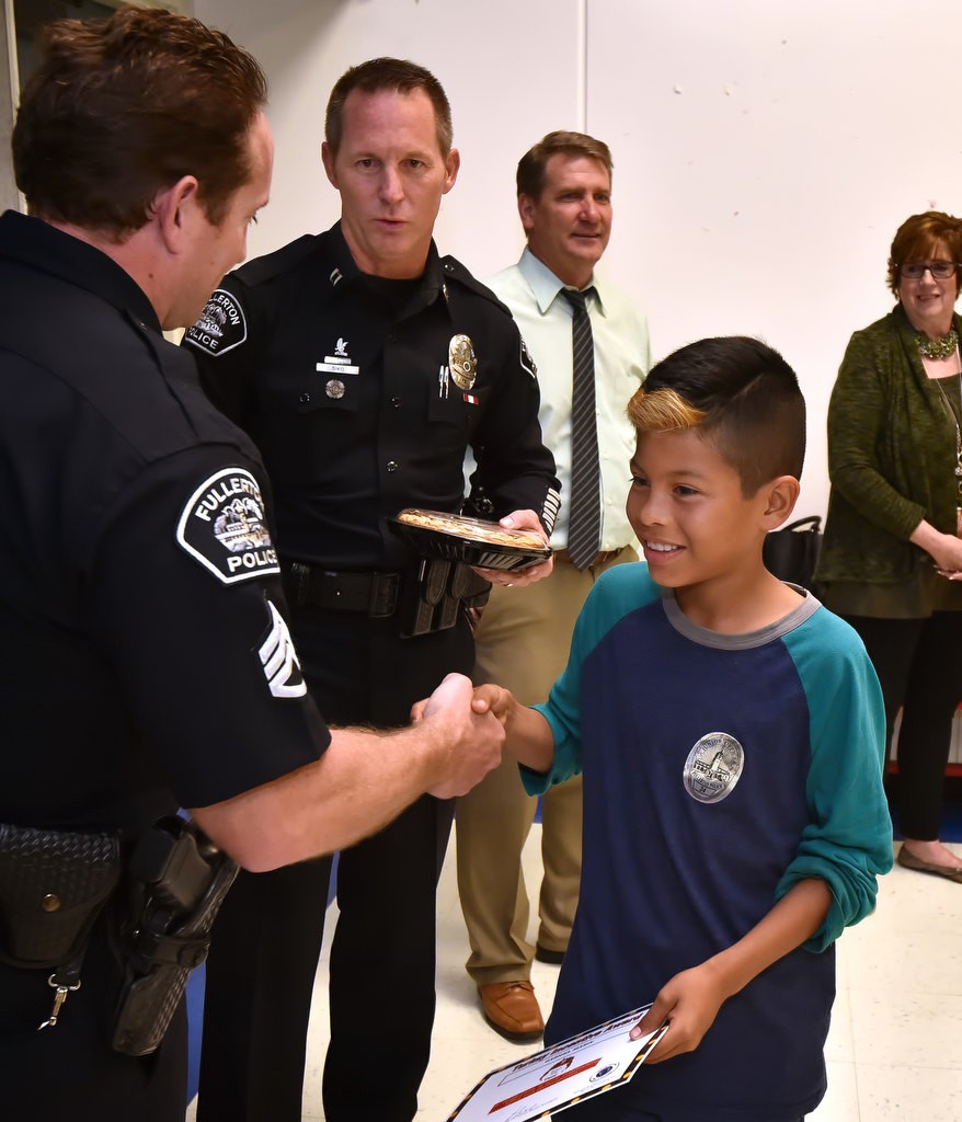 Ten-year-old Gabriel Marin is congratulated by Fullerton PD Sgt. Joel Craft during the Turkey Incentive, earning a Thanksgiving dinner for Gabriel’s family, at Valencia Park Elementary School. Photo by Steven Georges/Behind the Badge OC