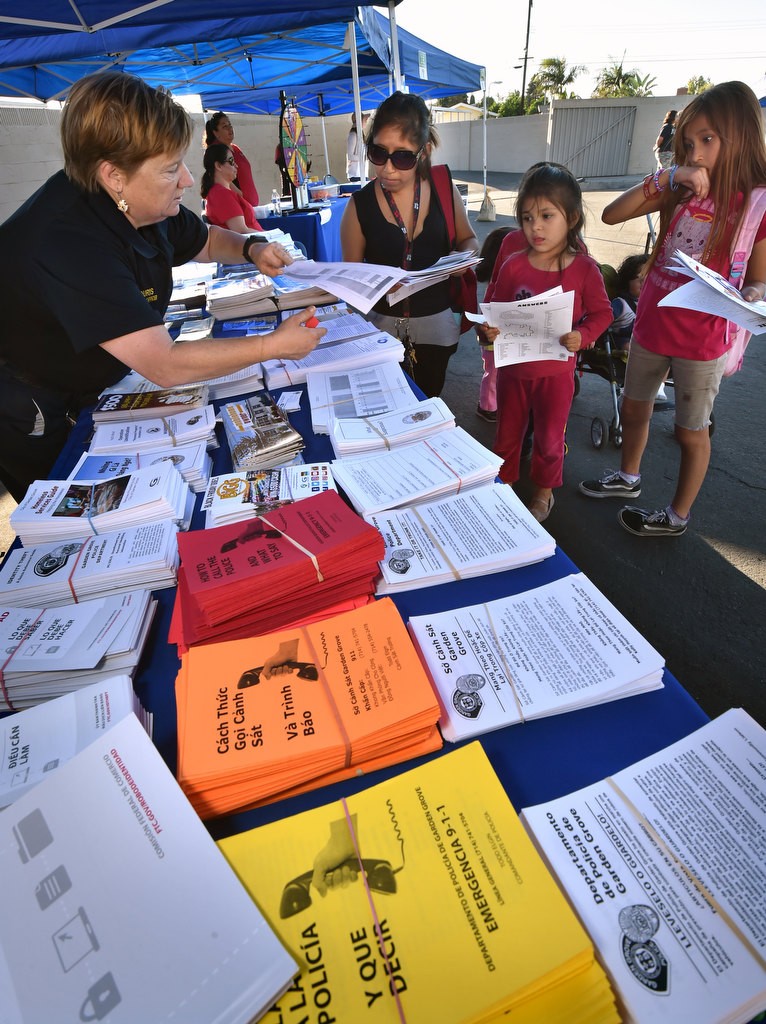 Garden Grove PD Community Service Officer Kris Backouris, left, talks to local residents as she hands out pamphlets on child safety and crime prevention in English, Spanish, Vietnamese and Korean during a Palma Vista/El Dorado Community Outreach Event. Photo by Steven Georges/Behind the Badge OC