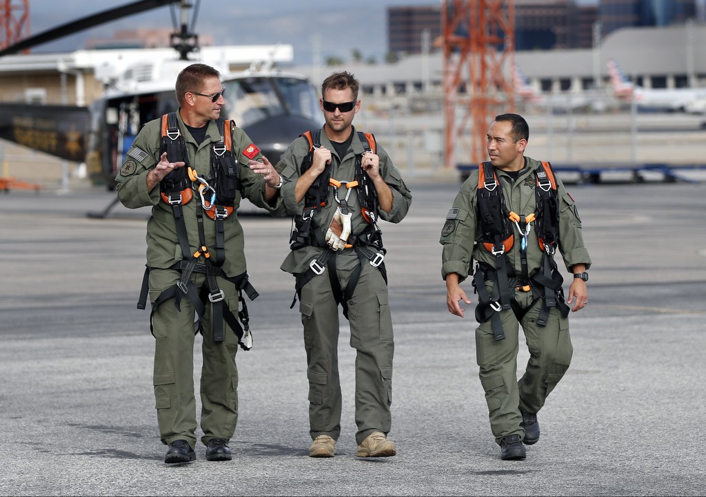 Jim Slikker, Alexander Bollhagen and Eddie Ochoa, from left, gear up for a training exercise on the Orange County Sheriff's Search and Rescue helicopter.     Photo by Christine Cotter/Behind the Badge OC
