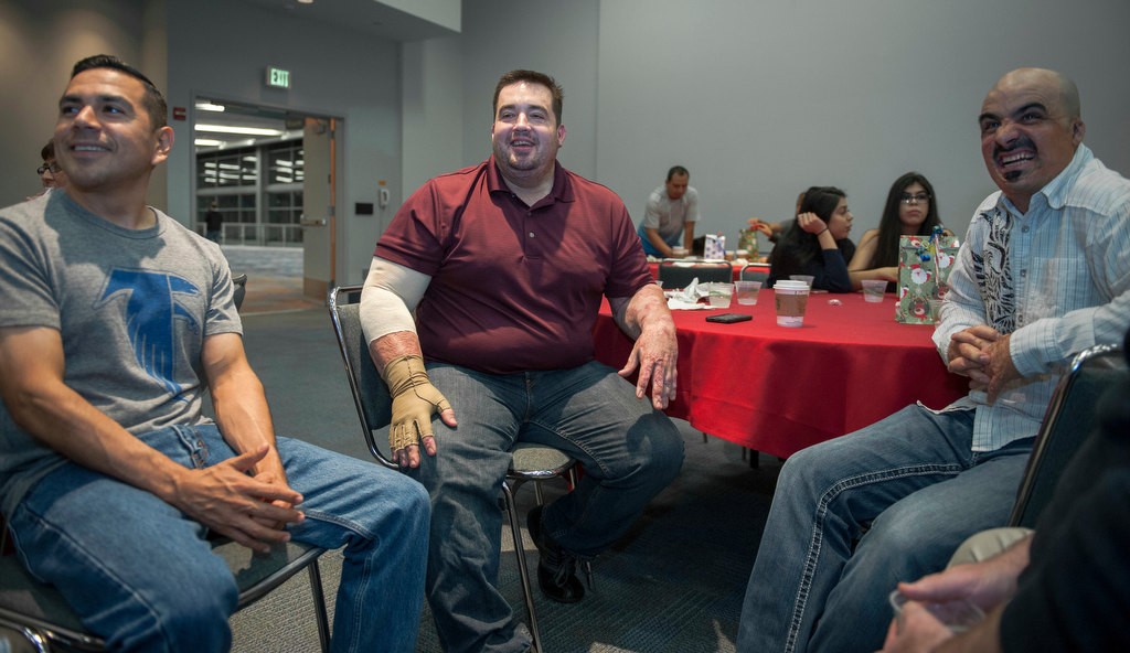 Johathan Molina, left, Jeremy Kelner and Carlos Frontal Jr. share stories at Mondays' annual party for burn survivors at the Anaheim Convention Center put on by the UC Irvine Health Regional Burn Center.