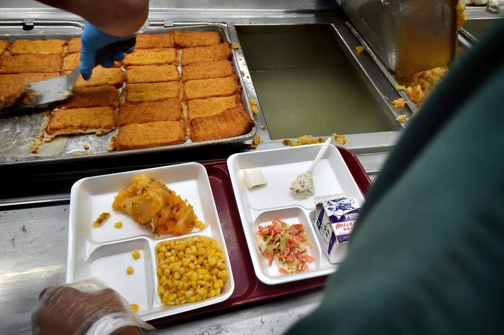 Fish is added to a plate of corn, potato and coleslaw at the Theo Lacy Facility for an upcoming meal. Inmate food preparers do not know which plate will be served any particular inmate. Photo by Steven Georges/Behind the Badge OC