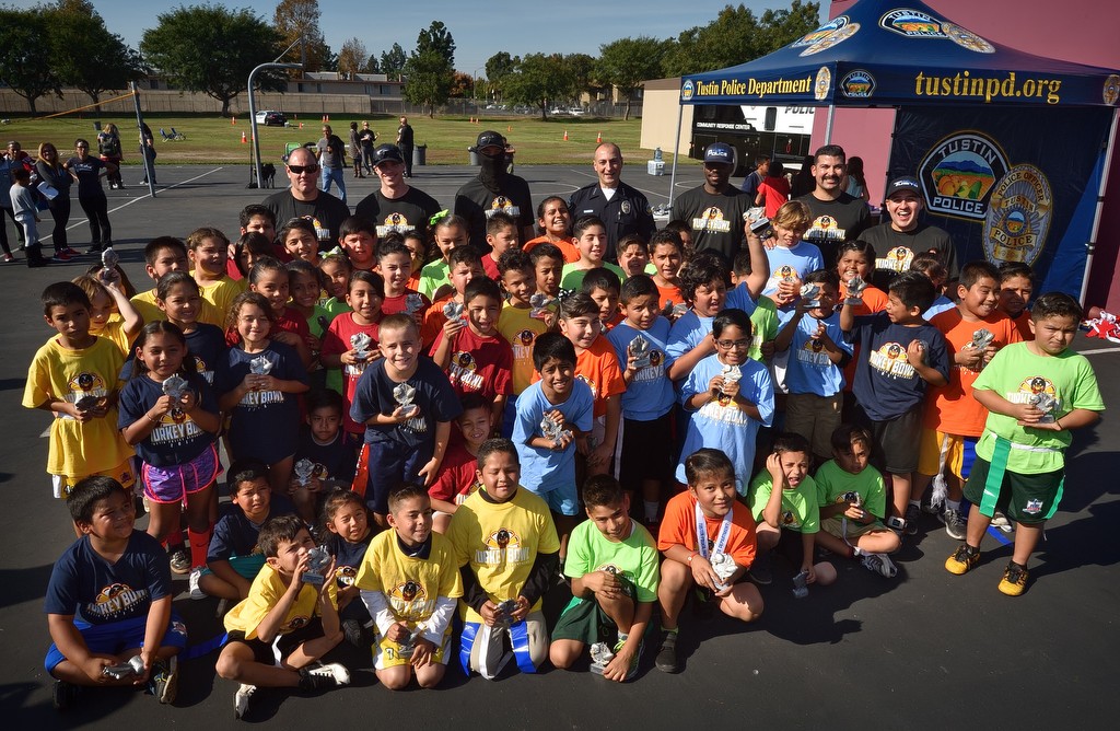 Kids gather with their coaches from Tustin PD and Tustin Police Chief Charles Celano, back center, after a flag football tournament at Heideman Elementary School. Photo by Steven Georges/Behind the Badge OC