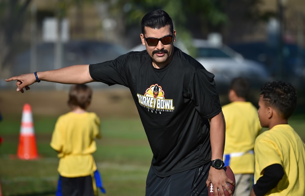 Tustin PD Officer Charles Carter works with kids from Heideman Elementary during a flag football tournament. Photo by Steven Georges/Behind the Badge OC