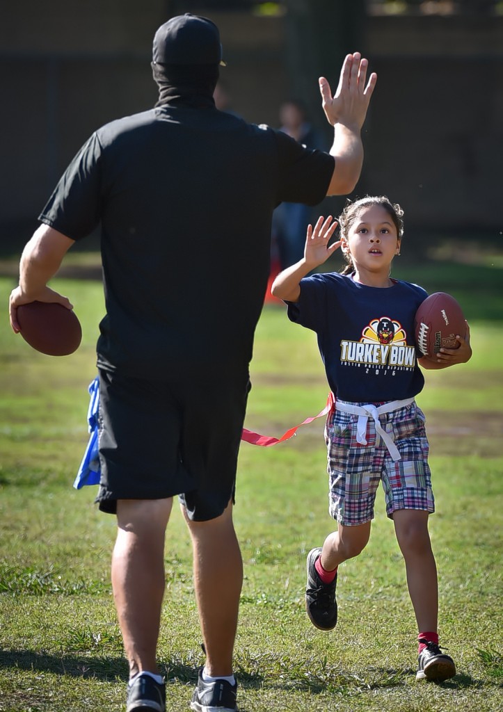 Tustin PD Officer Matt Roque gives a Heideman Elementary student after scoring a touchdown during a flag football tournament. Photo by Steven Georges/Behind the Badge OC