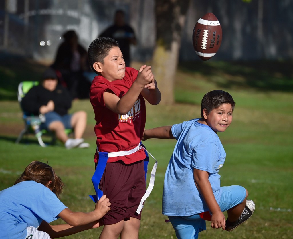 Kids leap for a pass during a flag football tournament coached by Tustin PD officers. Photo by Steven Georges/Behind the Badge OC