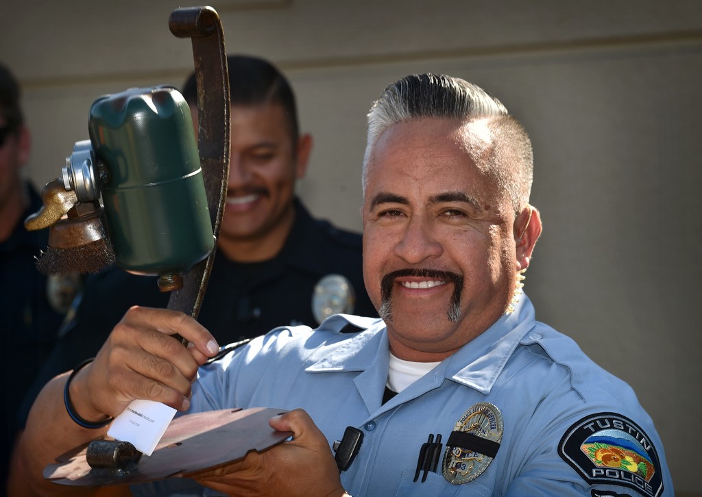 Tustin Police Services Officer John Garzone holds his trophy for the best mustache during the Tustin Police Office Association’s Stache for Cash mustache growing fundraiser contest. Photo by Steven Georges/Behind the Badge OC