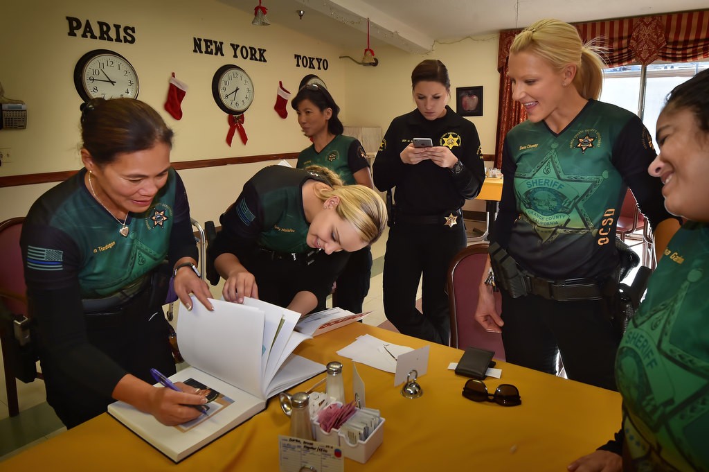 OC Sheriff Special Officers Jean Tindugan, left, and Dep. Norelly MejiaZea add photographs to Alice Chandler’s scrap book during a visit. Photo by Steven Georges/Behind the Badge OC