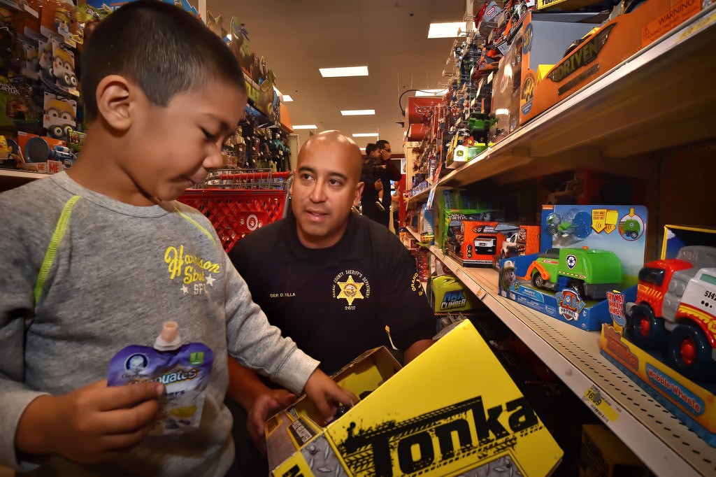 OC Sheriff Dep. Dan Villa helps Maddos Rodriguez, 5, look over toy trucks as they shop together during the Shop with a Deputy event at Target. Photo by Steven Georges/Behind the Badge OC
