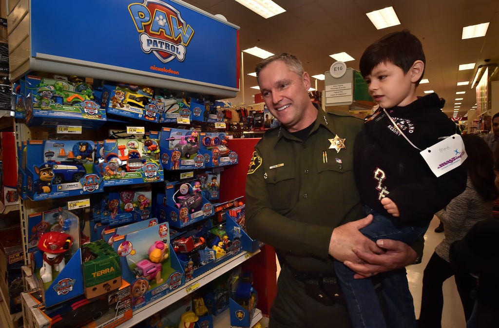 OC Sheriff Commander William Baker takes Cy Callan, 4, through the top area of Target during the Shop with a Deputy holiday event. Photo by Steven Georges/Behind the Badge OC