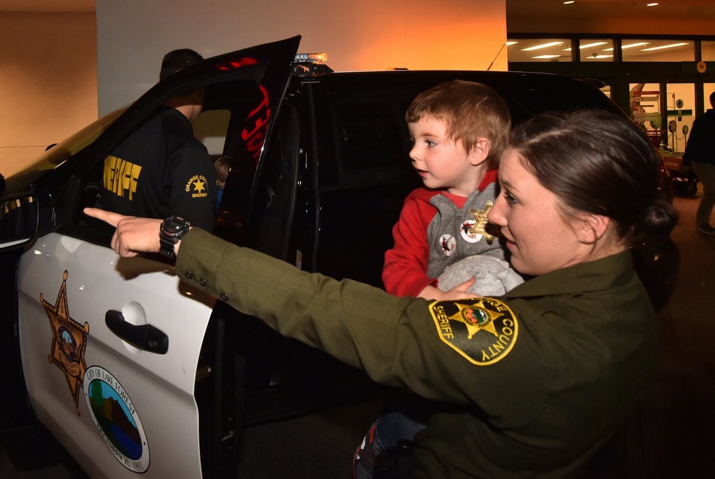 OC Sheriff Dep. Dallas Mihalik takes 3-year-old Aidyn McMullin on a tour of the sheriff patrol cars parked outside the Foothill Ranch Target. Photo by Steven Georges/Behind the Badge OC