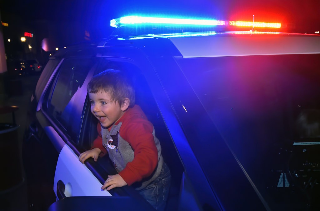 Three-year-old Aidyn McMullin has fun with an OC Sheriff patrol car, part of the Shop with a Deputy holiday event at the Foothill Ranch Target. Photo by Steven Georges/Behind the Badge OC