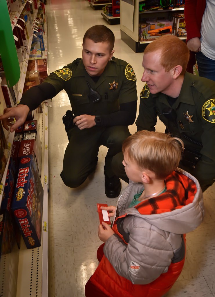 Eight-year-old Aiden Nolan gets some help picking out a game from OC Sheriff deputies Daniel Gonzalez, left, and Tyler Gish during a Shop with a Deputy event at the Target store in Foothill Ranch. Photo by Steven Georges/Behind the Badge OC