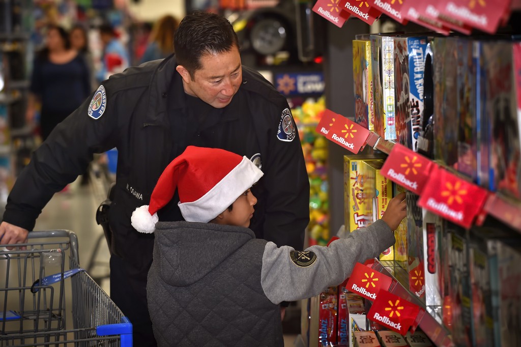 Eight-year-old Jonathon Valdez gets help picking out just the right board game from Westminster PD Officer Mike Ogawa during WPD’s annual Shop with a Cop event at Wal-Mart. Photo by Steven Georges/Behind the Badge OC