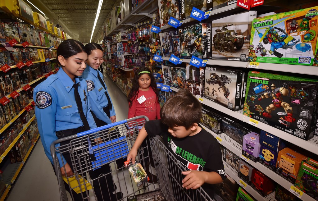 Westminster PD Explorers Grace Eusebio, left, and Thy Vu take Emma Gutierrez and Xxavier Ramerez, both 7, through the toy section of the local local the Wal-Mart Store for the annual Shop with a Cop event. Photo by Steven Georges/Behind the Badge OC