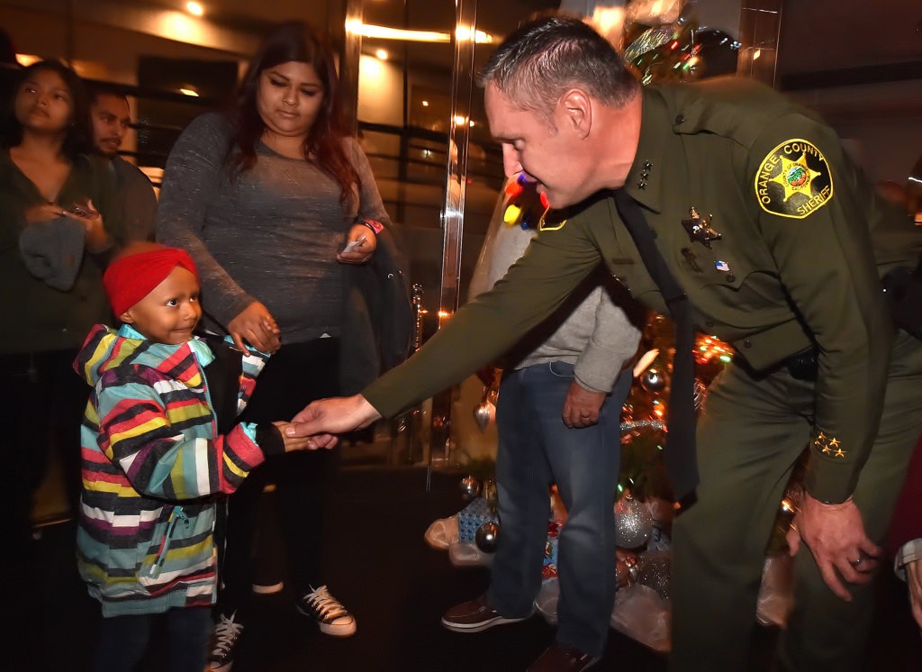 Orange County Undersheriff Don Barnes greets 5-year-old Adrina as she and the other kids board the Eternity during the Make A Wish Holiday Harbor Cruise. Photo by Steven Georges/Behind the Badge OC