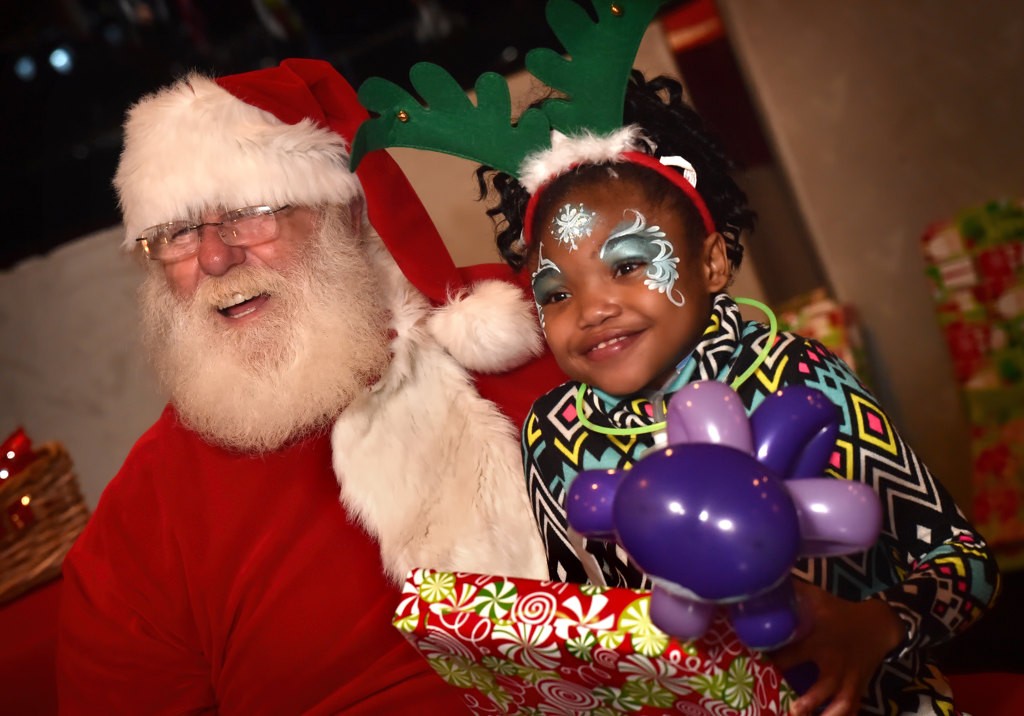 Jada Meakins, 11, flashes a big smile as she receives her gift from Santa during the Make A Wish Holiday Harbor Cruise. Photo by Steven Georges/Behind the Badge OC