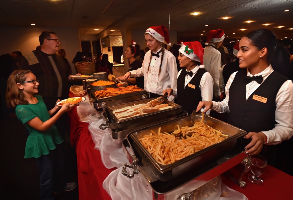 Aurora Medina, 10, gets a plate full of chicken, mac-n-cheese and hot dogs as the crew of Electra Cruises, Eternity, volunteer their time to serve the kids for the Make A Wish Holiday Harbor Cruise. Photo by Steven Georges/Behind the Badge OC