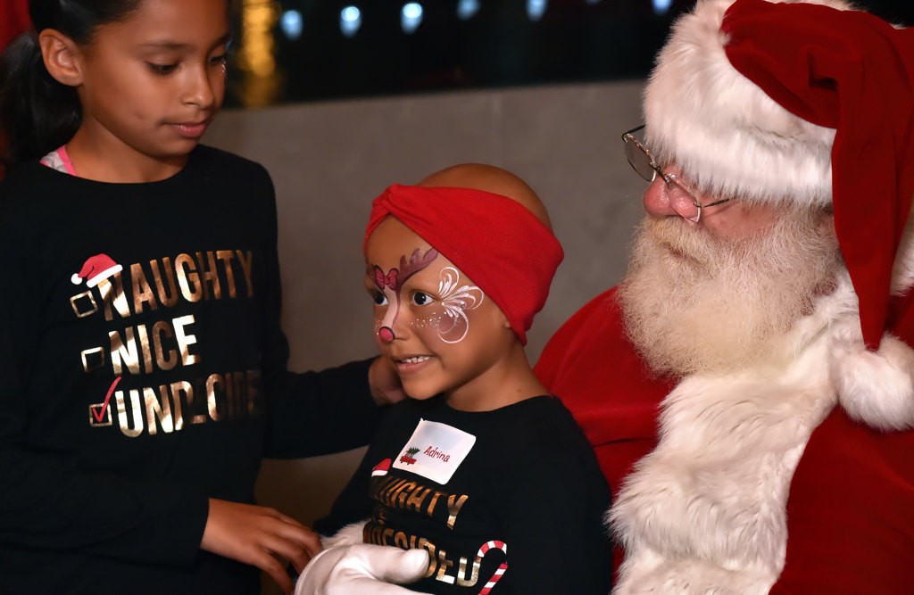 Five-year-old Adrina, center, gets her turn with Santa. Photo by Steven Georges/Behind the Badge OC