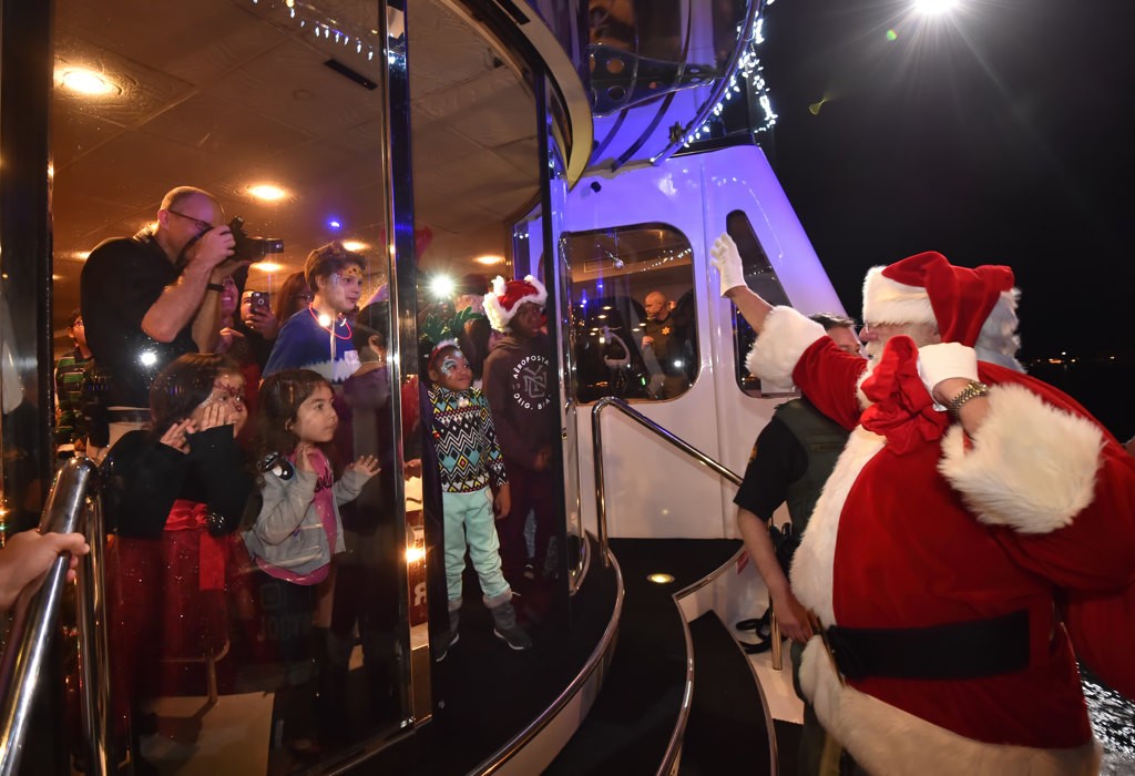Kids eagerly greet Santa as he hops on board the Eternity for the Make A Wish Holiday Harbor Cruise. Photo by Steven Georges/Behind the Badge OC