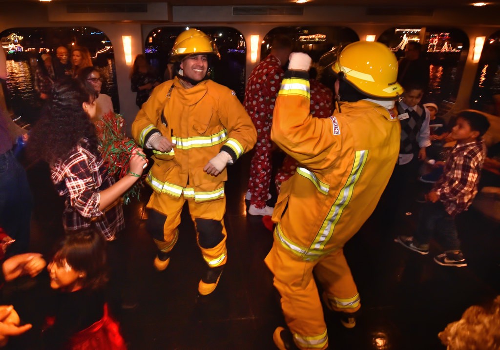 Orange County deputies Jay Wasserman and Blaze Bhency dance with guest while wearing OCSD firefighting outfits on board the Eternity for the Make A Wish Holiday Harbor Cruise. Photo by Steven Georges/Behind the Badge OC