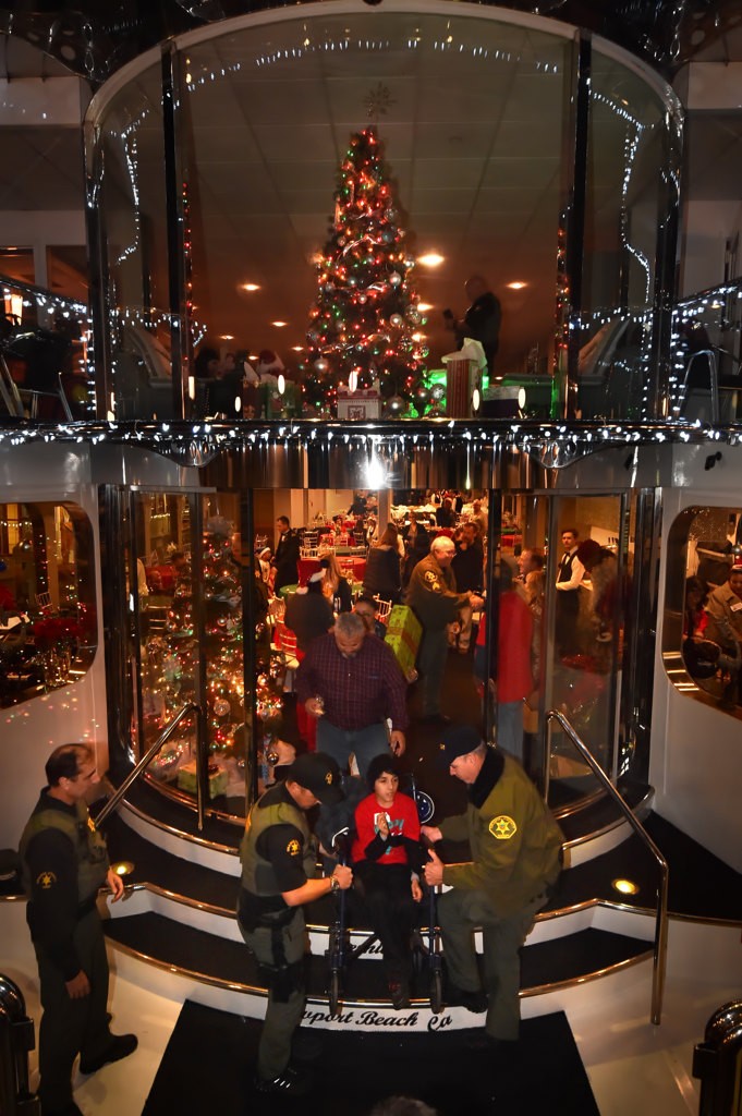 Orange County Sheriff Deputies help with guest on board the three story Eternity for the Make A Wish Holiday Harbor Cruise. Photo by Steven Georges/Behind the Badge OC