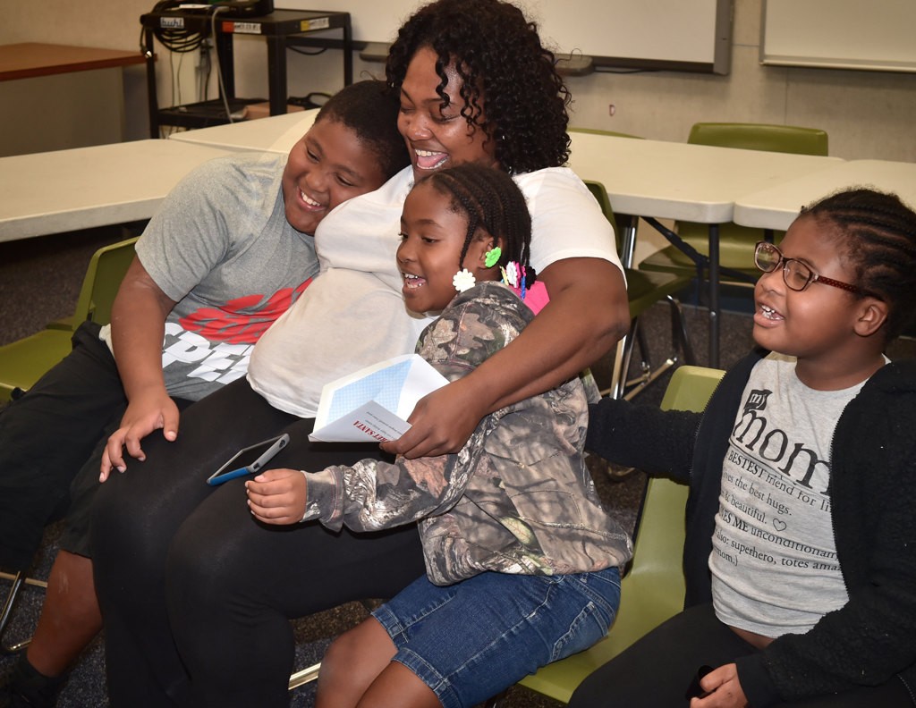 The Thompson family from left, David, Daleena, 7, and Kayla, 5, have a family hug after receiving their Operation Secret Santa holiday gift. Photo by Steven Georges/Behind the Badge OC