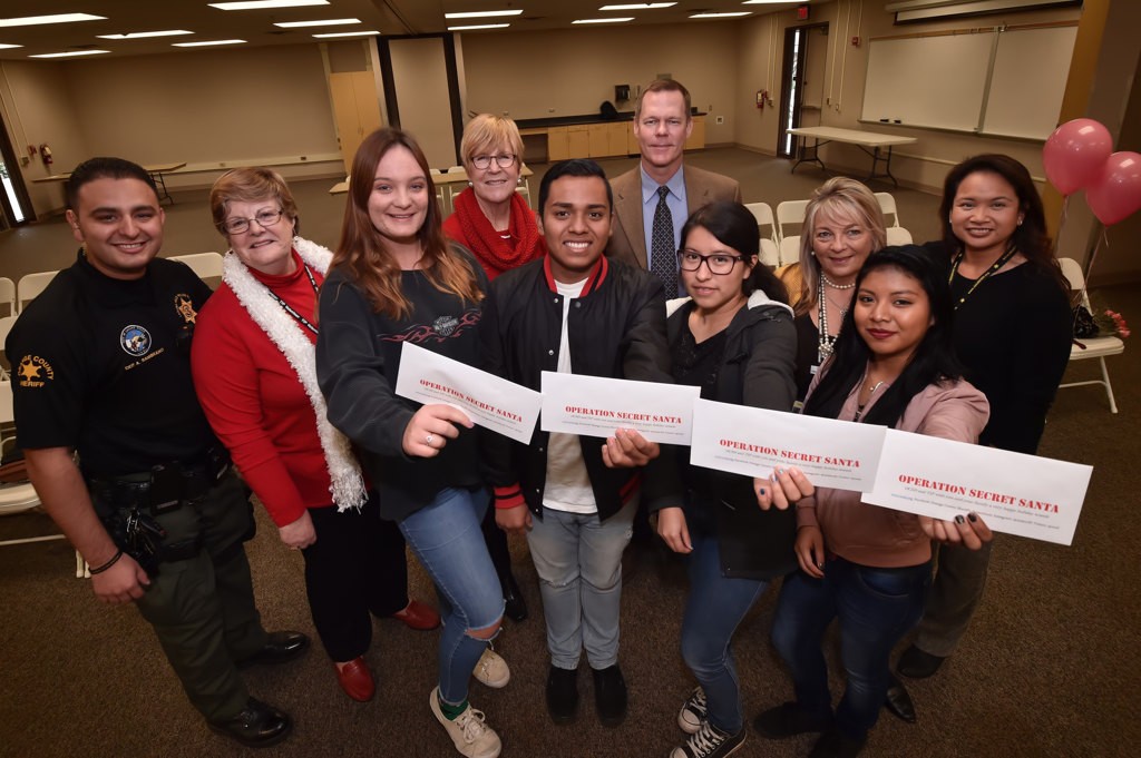 Audrey Carlin, Marvin Herrera, Jenifer and Elizabeth of Laguna Hills High hold their gifts of $500 each presented to them by OCSD Dep Anthony Sambrano, left, TIP volunteers and an anonymous donor. Photo by Steven Georges/Behind the Badge OC