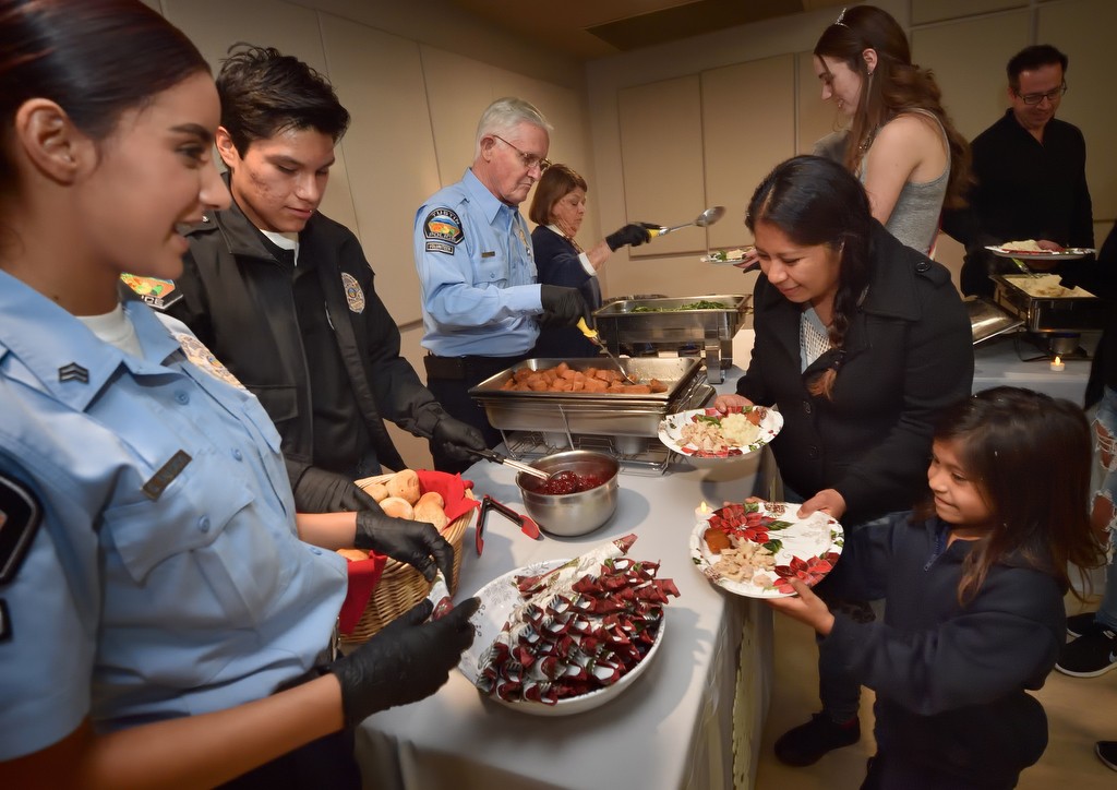 Explorers Getzemany Salgado, left, and Emmanuel Araujo help serve turkey dinners to families as part of Tustin PD’s annual Santa Cop gathering.  Photo by Steven Georges/Behind the Badge OC