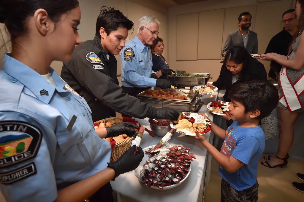 Explorers Getzemany Salgado, left, and Emmanuel Araujo help serve turkey dinners to families as part of Tustin PD’s annual Santa Cop gathering.  Photo by Steven Georges/Behind the Badge OC