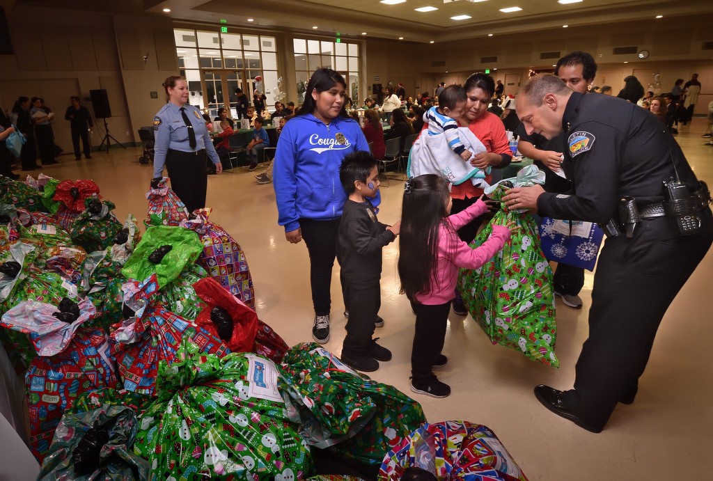 The Asael family walks up to receive their Christmas presents from Tustin Chief Charles Celano at the conclusion of Tustin PD’s annual Santa Cop event at the Tustin Community Center. Photo by Steven Georges/Behind the Badge OC