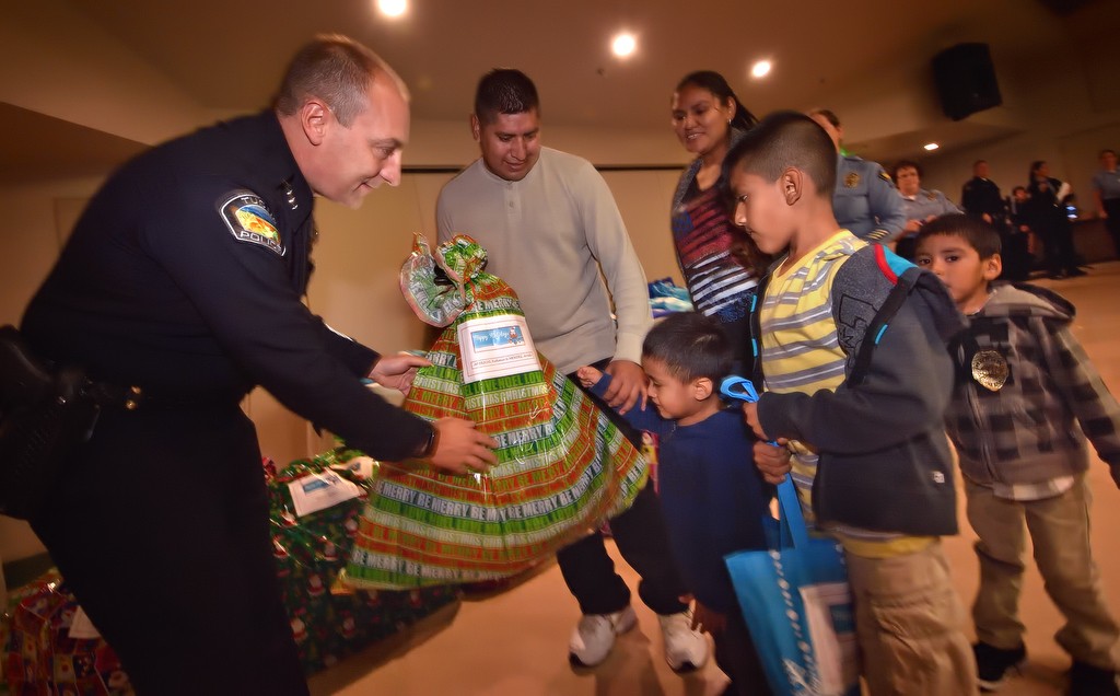 The Arcdi family receives their Christmas presents from Tustin Chief Charles Celano during Tustin PD’s annual Santa Cop event. Photo by Steven Georges/Behind the Badge OC