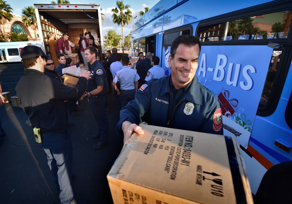 Firefighter/Paramedic Mike Patterson of Anaheim Fire & Rescue joins other firefighters as they unload boxes of toys during the Spark of Love Toy Drive at the Honda Center. Photo by Steven Georges/Behind the Badge OC