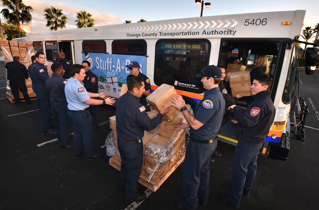 Firefighters lineup to fill OCTA buses with toys for the Spark of Love Toy Drive at the Honda Center. Photo by Steven Georges/Behind the Badge OC