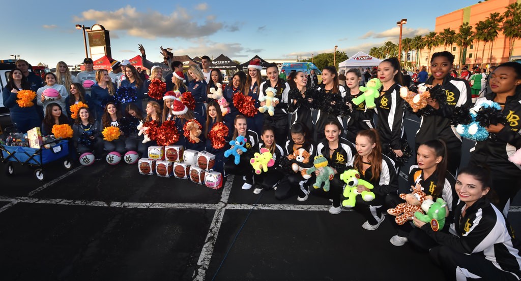 Cheer team members from Cal State Fullerton, left, and Long Beach State gather for the Spark of Love Toy Drive at the Honda Center. Photo by Steven Georges/Behind the Badge OC