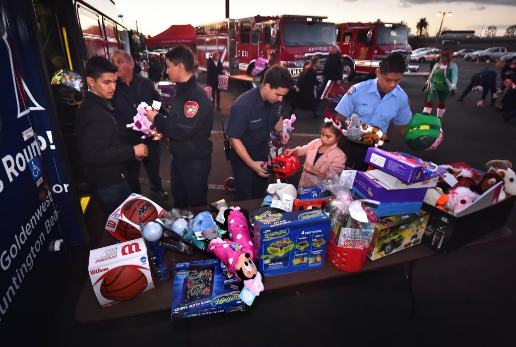 Firefighters lineup to fill OCTA buses with toys for the Spark of Love Toy Drive at the Honda Center. Photo by Steven Georges/Behind the Badge OC