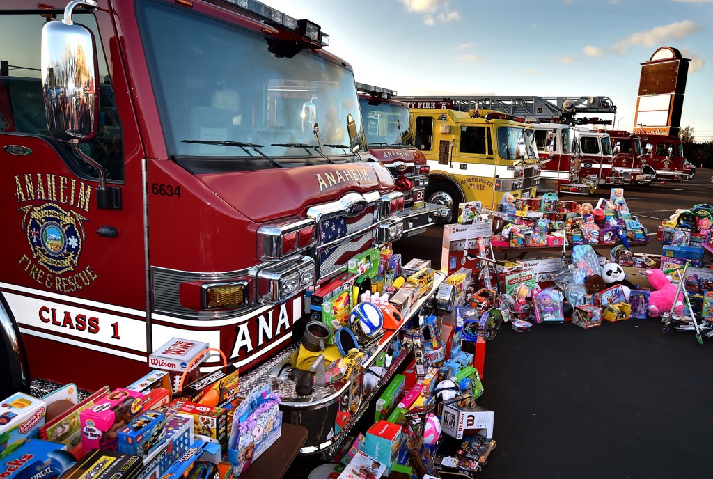 Fire trucks and engines from Anaheim, Garden Grove, Orange City, Huntington Beach and Orange County lineup in front of toys collected for the Spark of Love Toy Drive at the Honda Center. Photo by Steven Georges/Behind the Badge OC