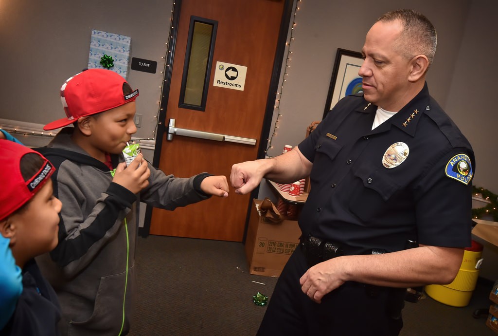 Anaheim Police Chief Raul Quezada encourages Robert Turcios, 8, left, and his brother Michael Turcios, 10, who told him they want to become police officers when they get older, as families father for OCFJC’s Adopt A Family event. Photo by Steven Georges/Behind the Badge OC