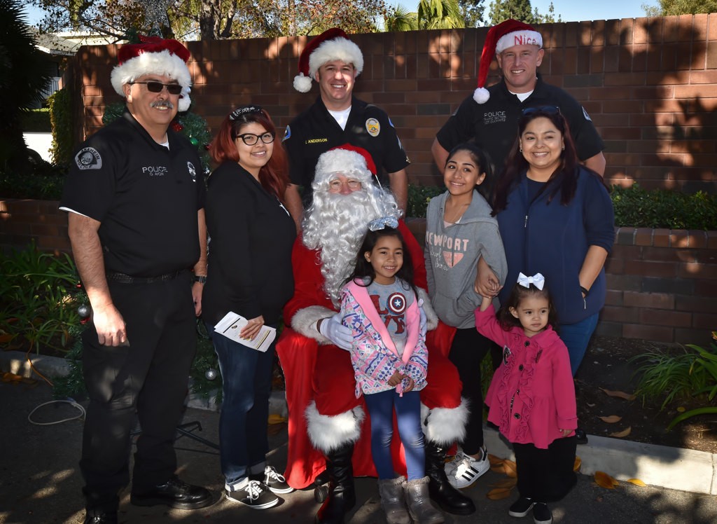 Anaheim PD officers Oscar Ayon, left, Eric Anderson and Sgt. Rodney Duckwitz have their photo taken with Santa and families who came to have their car seat inspected. Photo by Steven Georges/Behind the Badge OC